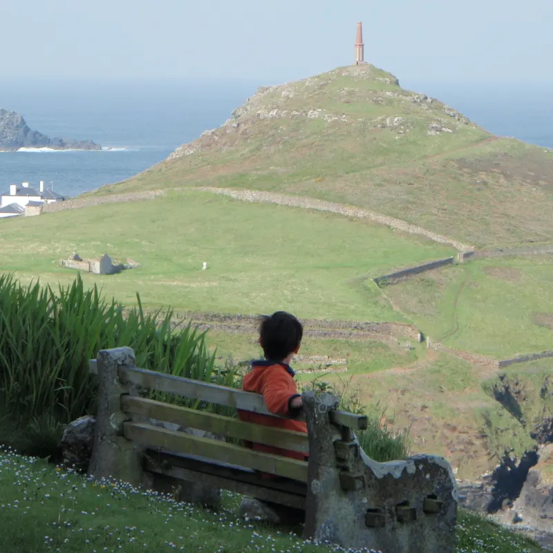 child sitting on front bench of Wheal Call holiday rental looking out towards Cape Cornwall