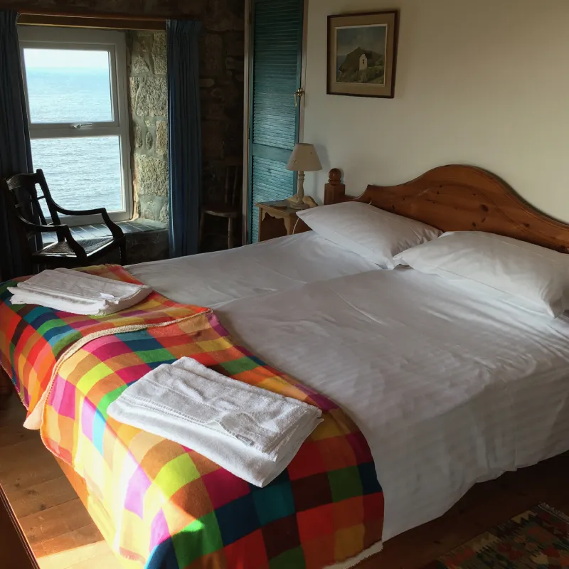 Main bedroom of Wheal Call holiday accommodation showing superking bed and view out of front window with panoramic sea views