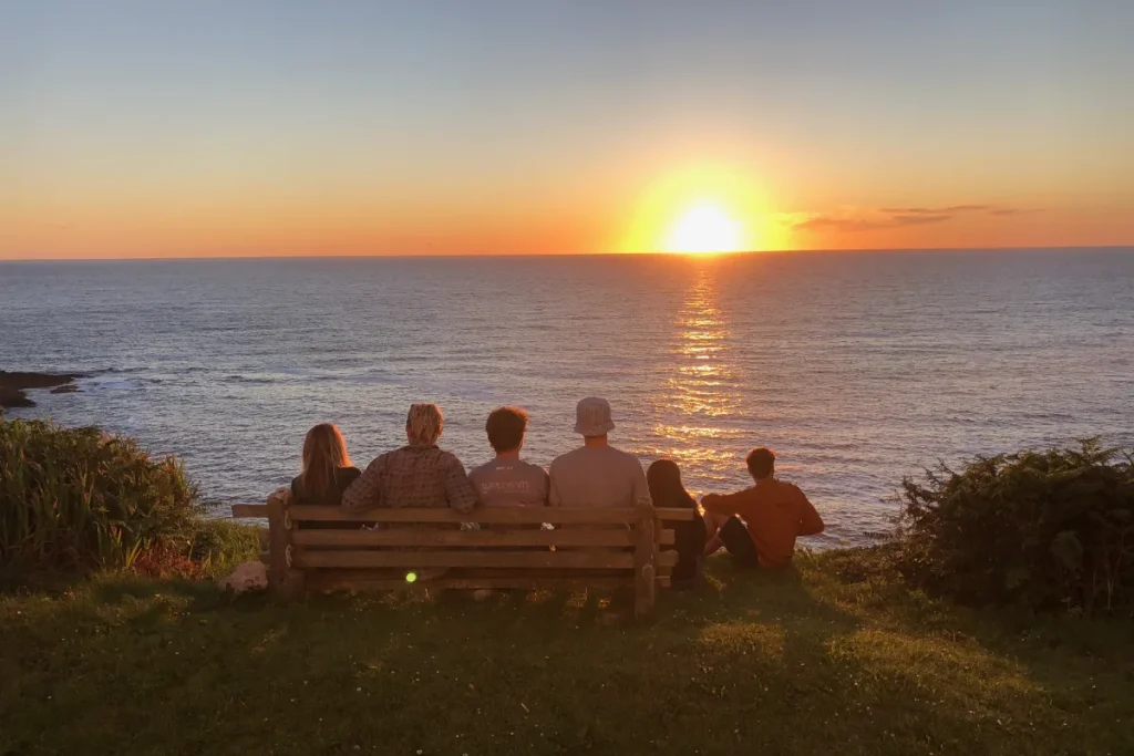 Photo of young friends on the bench at Wheal Call looking out towards the setting sun